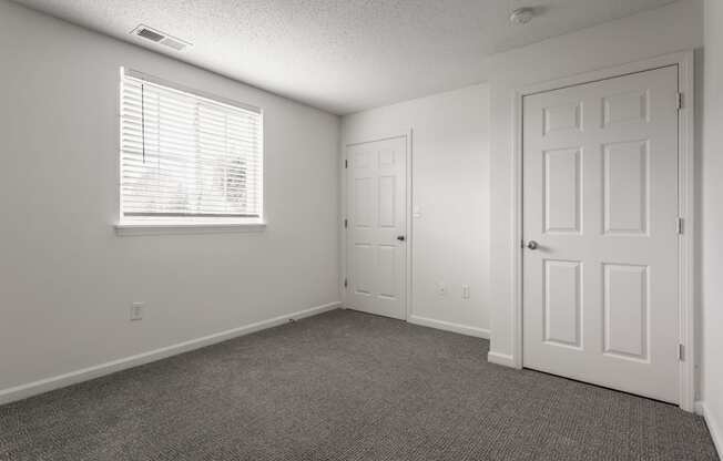 an empty living room with a white door and a window