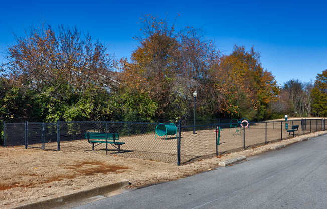 A park with a fence, bench, and trees.