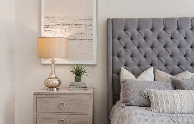 a bedroom with a bed with a tufted headboard and a night stand