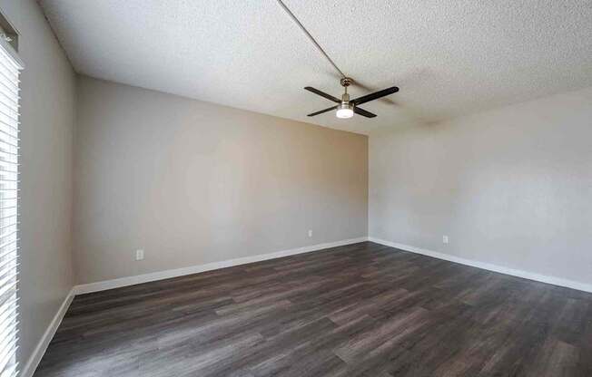 A room with a ceiling fan and wooden flooring.