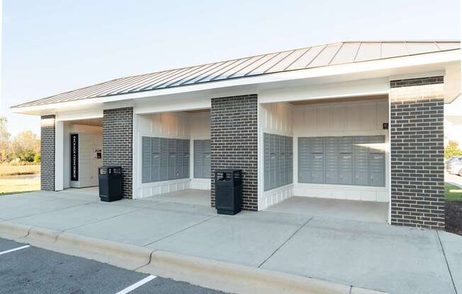 A building with a white and black facade has a metal roof and two black trash cans in front.