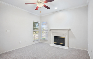 an empty living room with a fireplace and a ceiling fan at La Ventura Apartments, Plano, TX, 75093