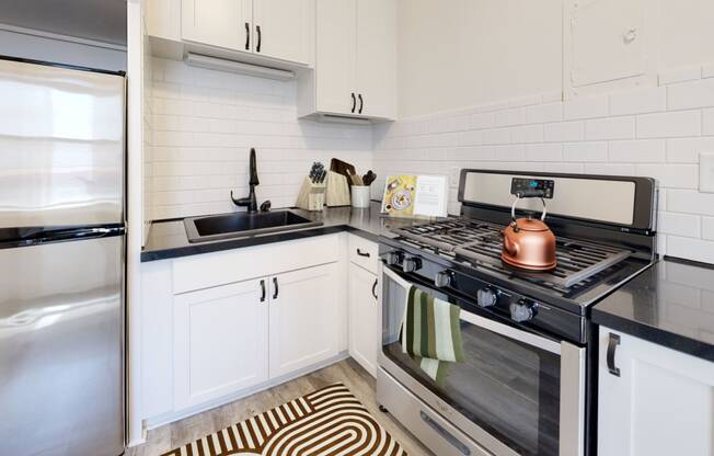 a kitchen with white cabinets and a black and white rug