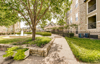 View of Walking Trails, Showing Fountain, Landscaping, and Fenced-In Area at Stonebriar of Frisco Apartments