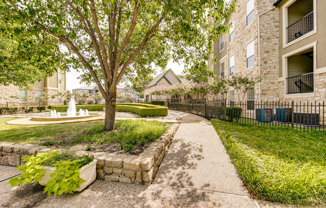 View of Walking Trails, Showing Fountain, Landscaping, and Fenced-In Area at Stonebriar of Frisco Apartments