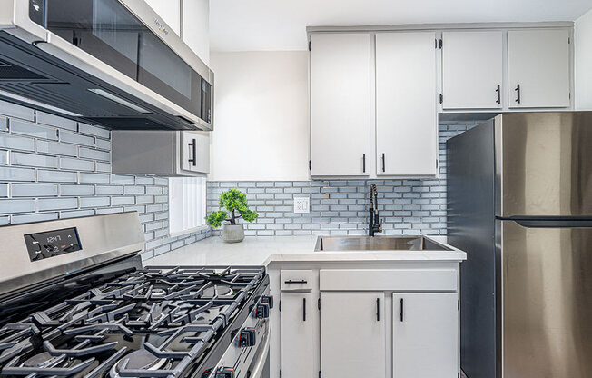 Tiled kitchen with stainless steel fridge, oven, and miocrowave.
