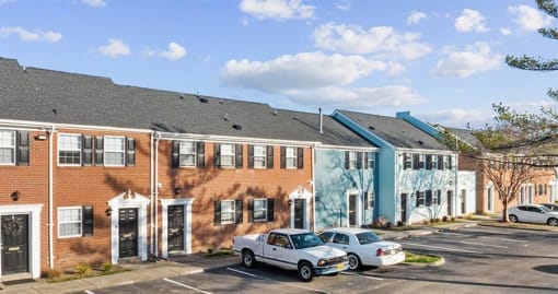 a row of buildings with cars parked in a parking lot