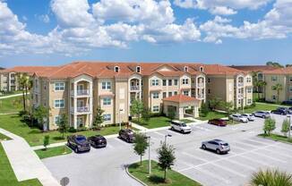 an image of an apartment complex with cars parked in a parking lot