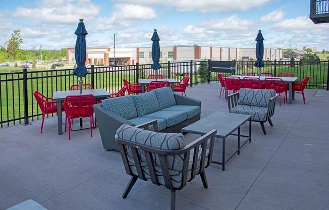 A patio with red chairs and blue umbrellas.