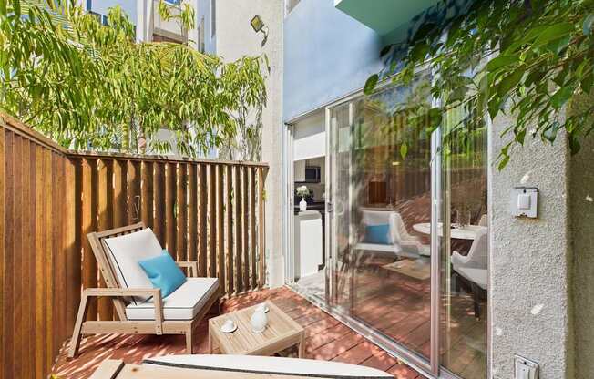 A wooden chair with a blue pillow sits on a patio.