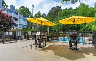 A pool area with two yellow umbrellas and a table.