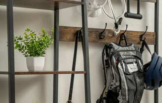 a metal shelving unit with hooks and a backpack on it and plants on the shelves