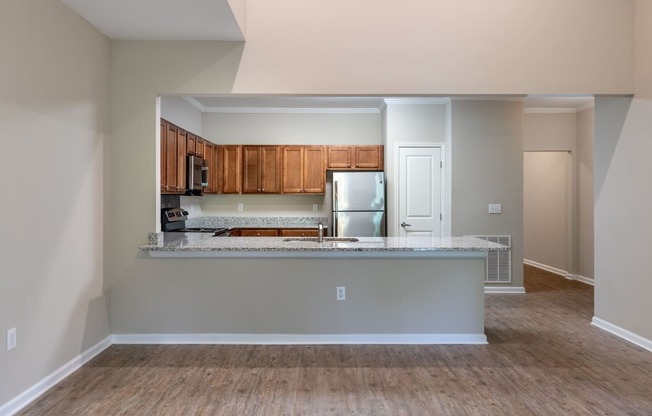 an empty living room with a kitchen with wood flooring