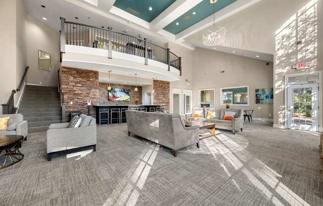 the lobby of a clubhouse with couches and chairs and a fireplace