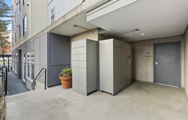 a private entrance area two package lockers and a potted plant on the side of a building at Promenade at the Park Apartment Homes, Seattle, Washington 98125