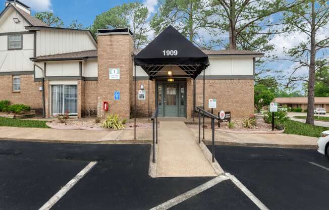 a brick building with a black awning and stairs in front of a driveway