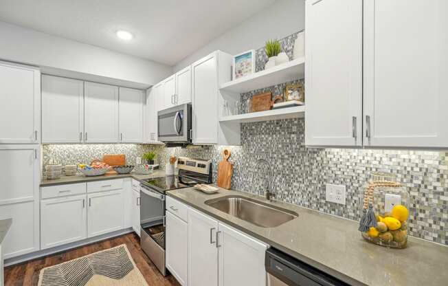 a kitchen with white cabinets and a stainless steel sink