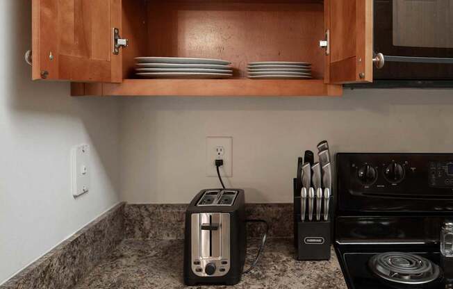 A kitchen with a toaster and knives on the counter.