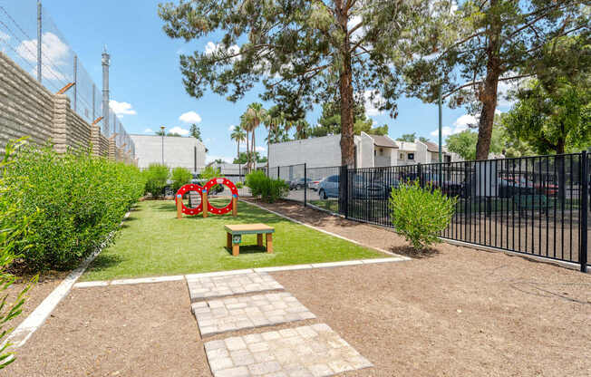 A small garden with a bench and a red sculpture.