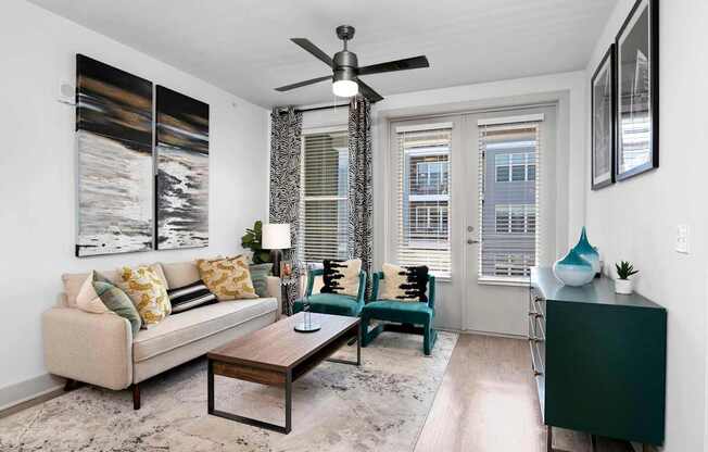 A living room with a beige couch, a coffee table, and a ceiling fan.