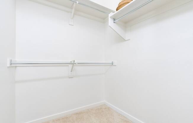 a white closet with a shelf and a hanging rail on the wall