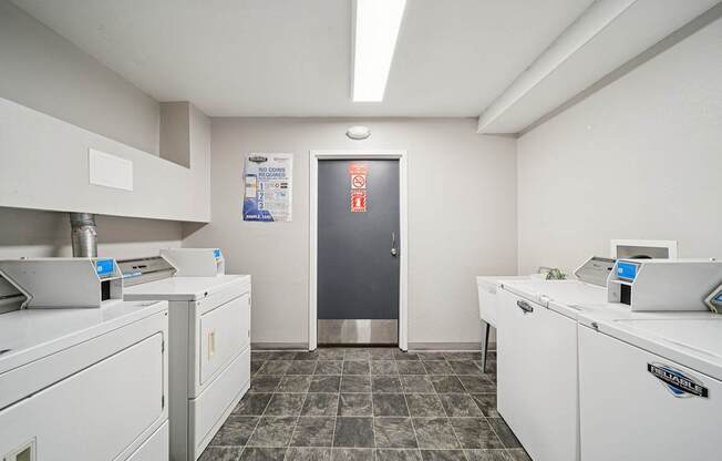 A clean, white-walled kitchen with a stainless steel refrigerator and a tiled floor.