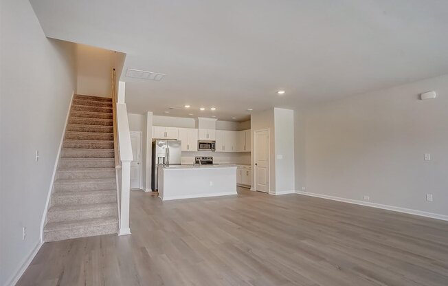 an empty living room with a staircase in the background