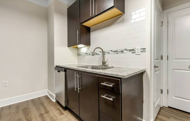 a kitchen with dark cabinets and a sink and a faucet