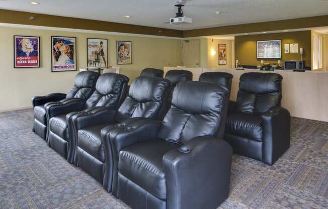 Rows of leather chairs and movie posters on the wall of a theater room