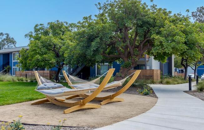 two hammocks sitting on the sidewalk in front of a building