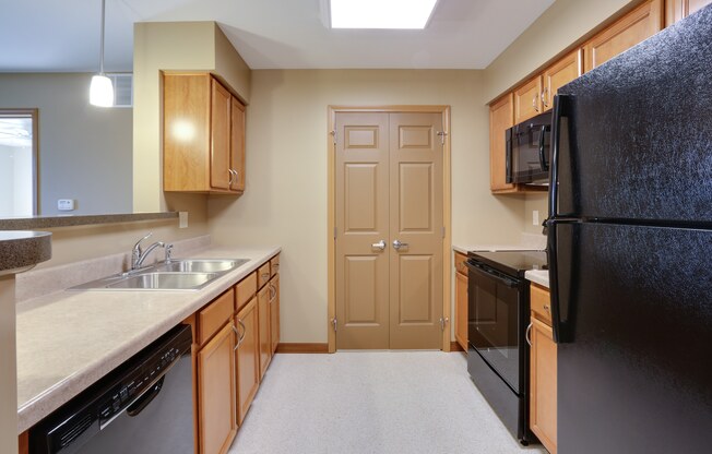 an empty kitchen with a black refrigerator and a sink