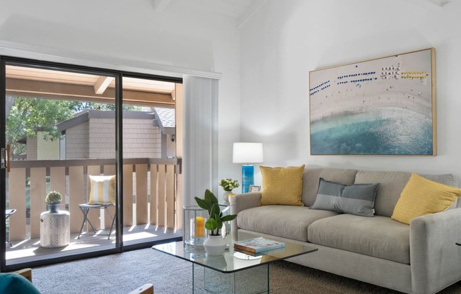 a living room with a couch and a glass coffee table and a sliding glass door