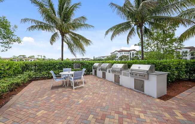 a patio with a table and chairs and two gas grills