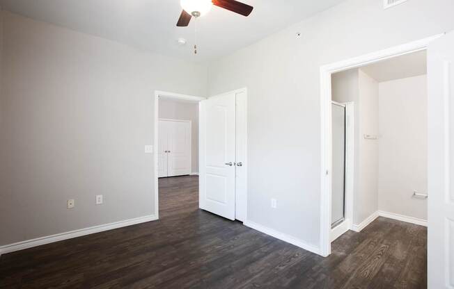 A room with a ceiling fan and wood flooring.