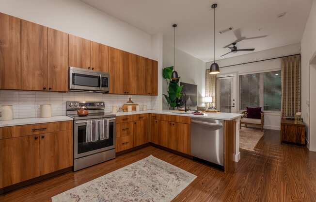 2-Bedroom Apartments in Old East Dallas, TX - 4600 Ross - Kitchen with Hardwood-Style Flooring, Wood Cabinets, White Countertops, White Tile Backsplash, and Stainless Steel Appliances