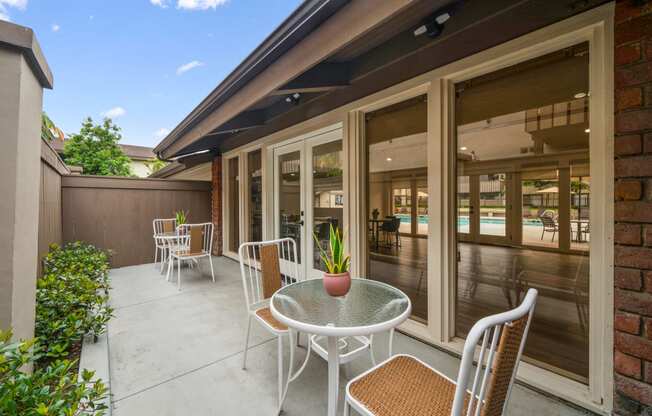 a patio with a table and chairs and a pool in the background