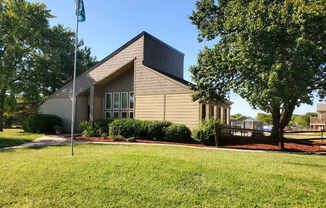 Willow Creek Apartments - Exterior view of the clubhouse with lush landscaping.
