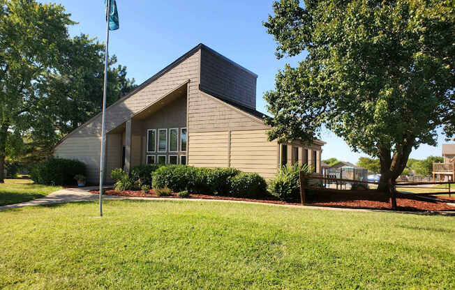 Willow Creek Apartments - Exterior view of the clubhouse with lush landscaping.