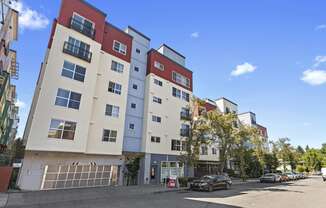 an apartment building with a parking lot in the foreground and a blue sky in the background at Promenade at the Park Apartment Homes, Seattle, 98125