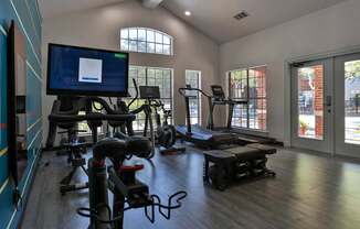 A gym with exercise equipment and a television displaying a webpage.