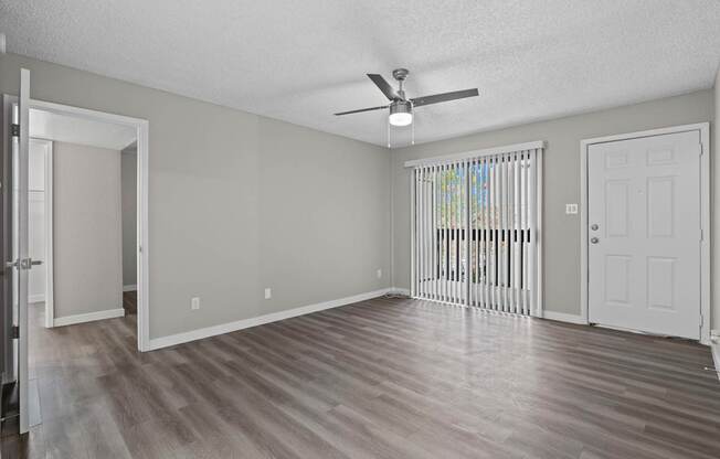 A room with a ceiling fan and a window with blinds.