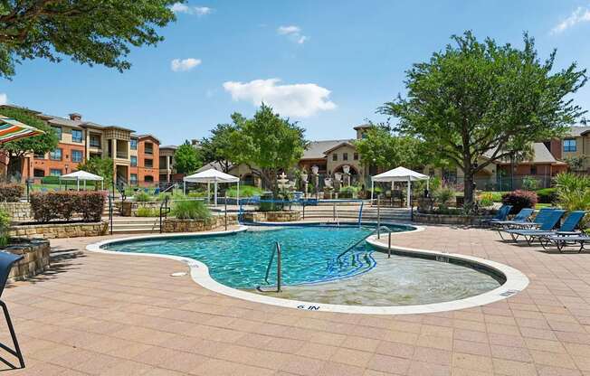 A round pool surrounded by a brick patio and lounge chairs.