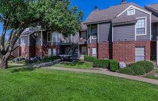 a house with a lawn in front of a brick building