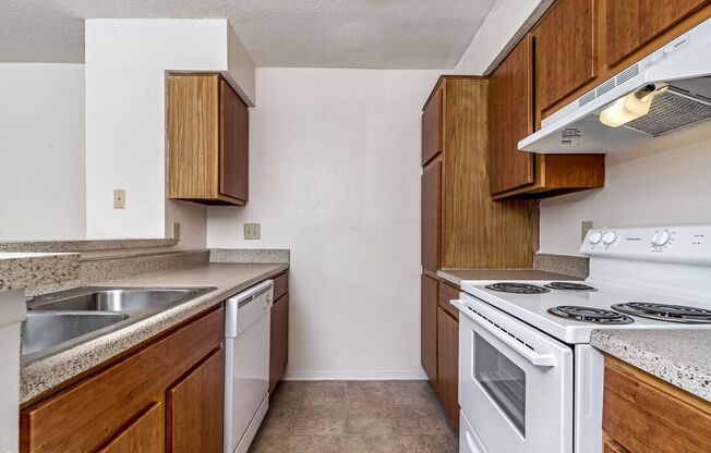 A kitchen with a white stove top oven and wooden cabinets.