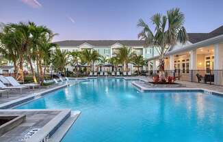 A large swimming pool surrounded by palm trees and lounge chairs.