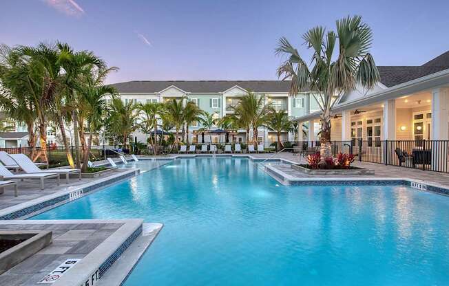 A large swimming pool surrounded by palm trees and lounge chairs.