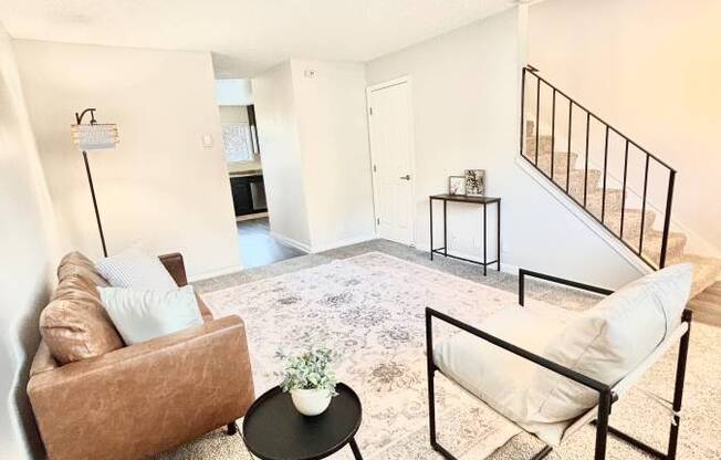 Campbell Plaza Apartments
710 Nido Drive, Campbell, CA 95008. A living room with a brown couch, a white chair, and a small table with a plant on it.