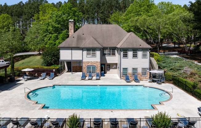 a large pool in front of a house with chairs around it