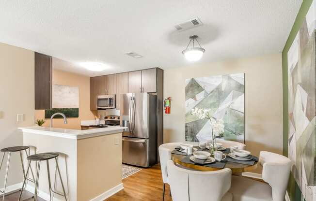an open kitchen and dining room with stainless steel appliances and a table and chairs at Crossgates Apartment Homes, Starkville, MS