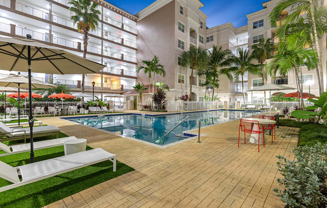 A pool area with a table and chairs and umbrellas.